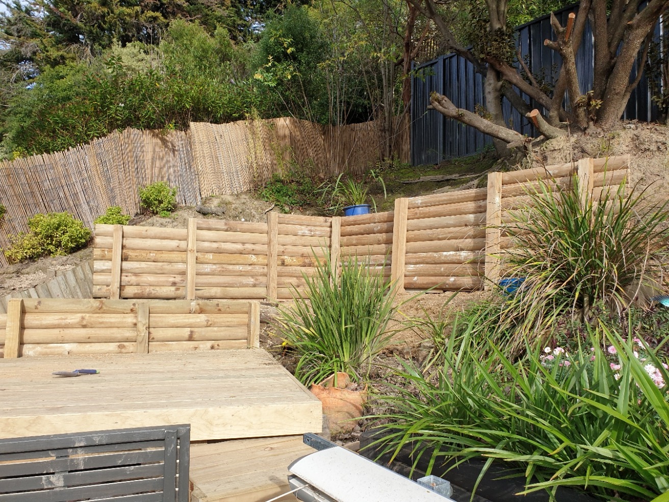 Curved timber sleeper retaining walls among established planting