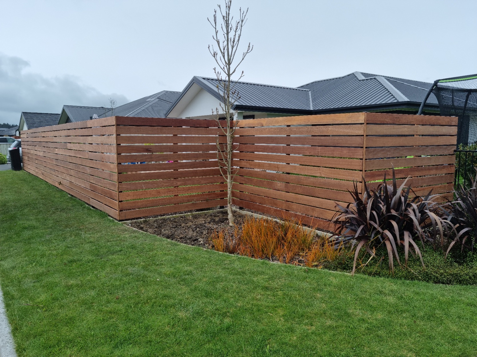 Horizontal timber slat fence wrapping a landscaped garden