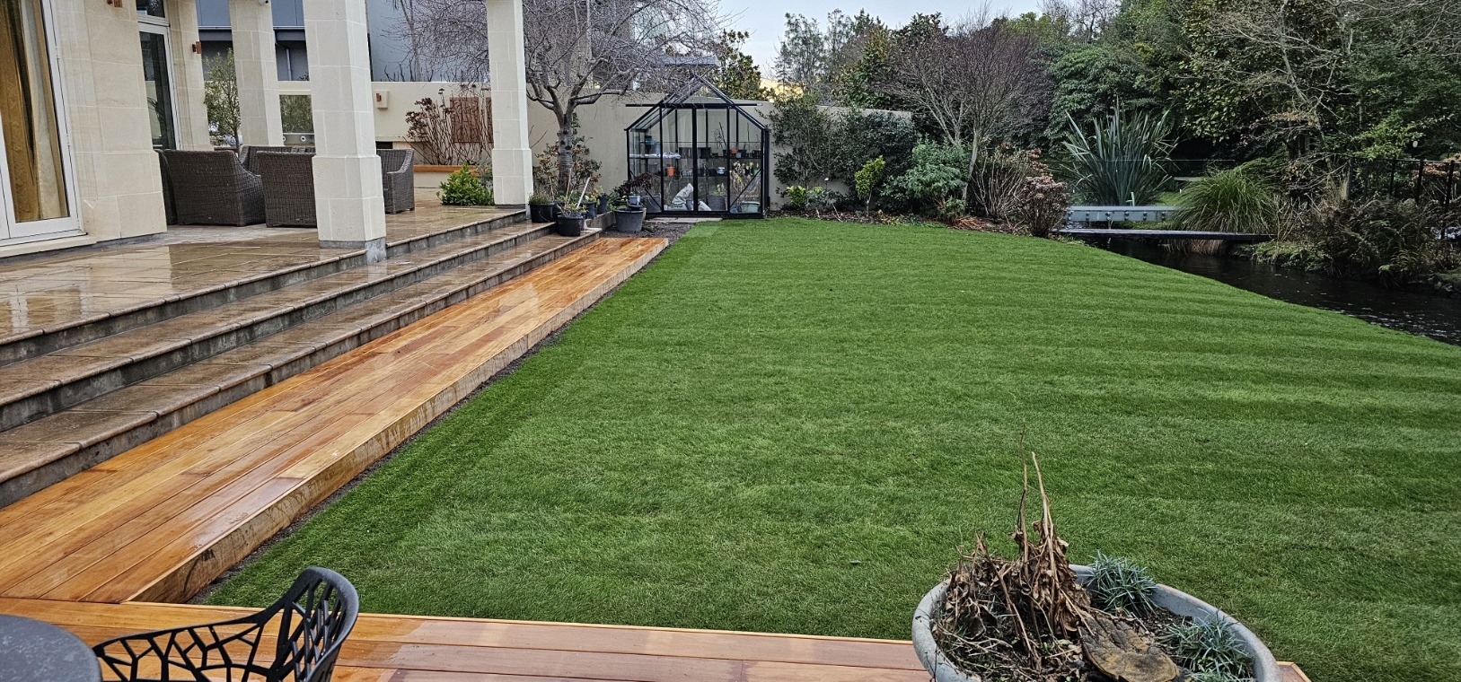 Fresh lawn bordered with timber beside a garden and patio