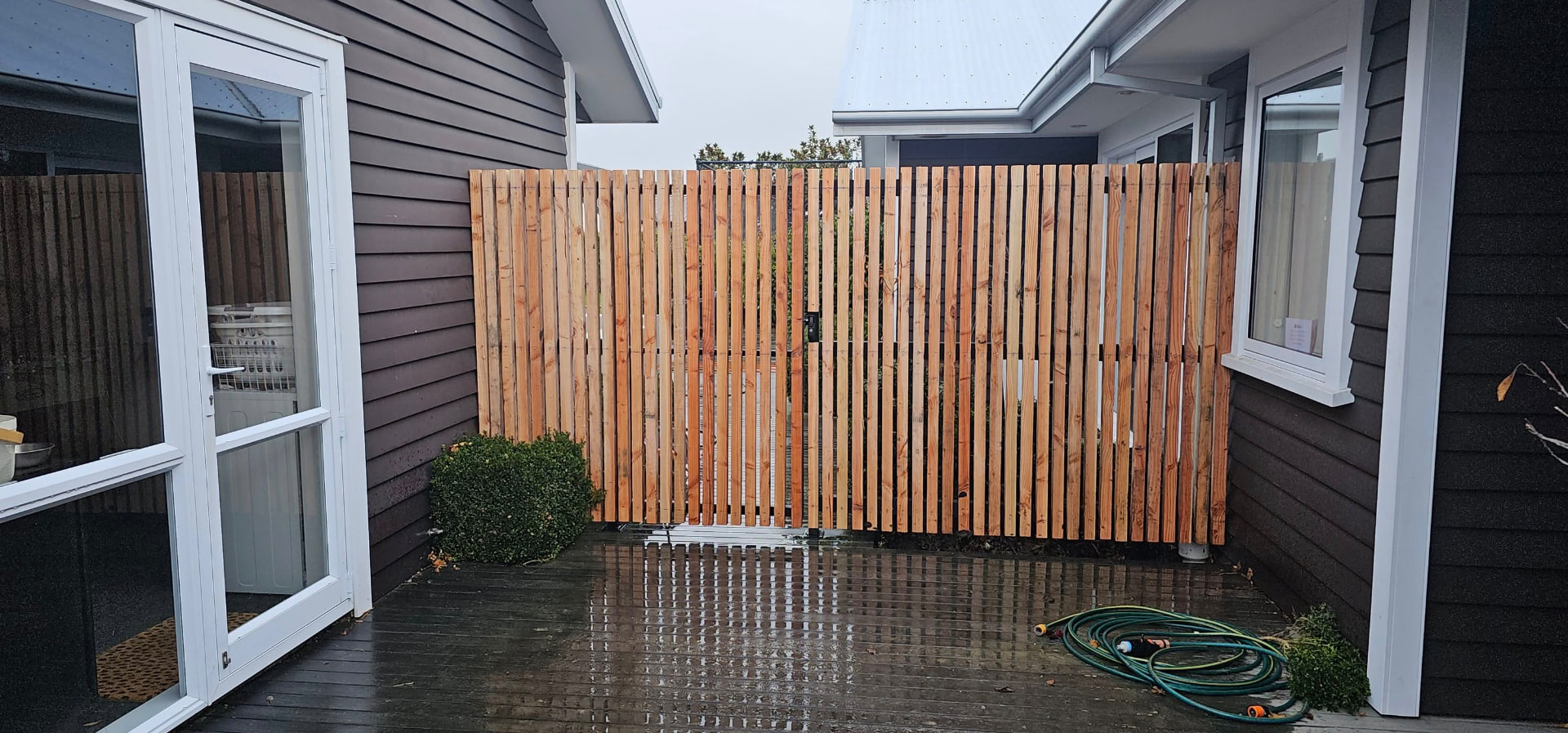 Timber slat fence and gate beside a deck at a New Zealand home