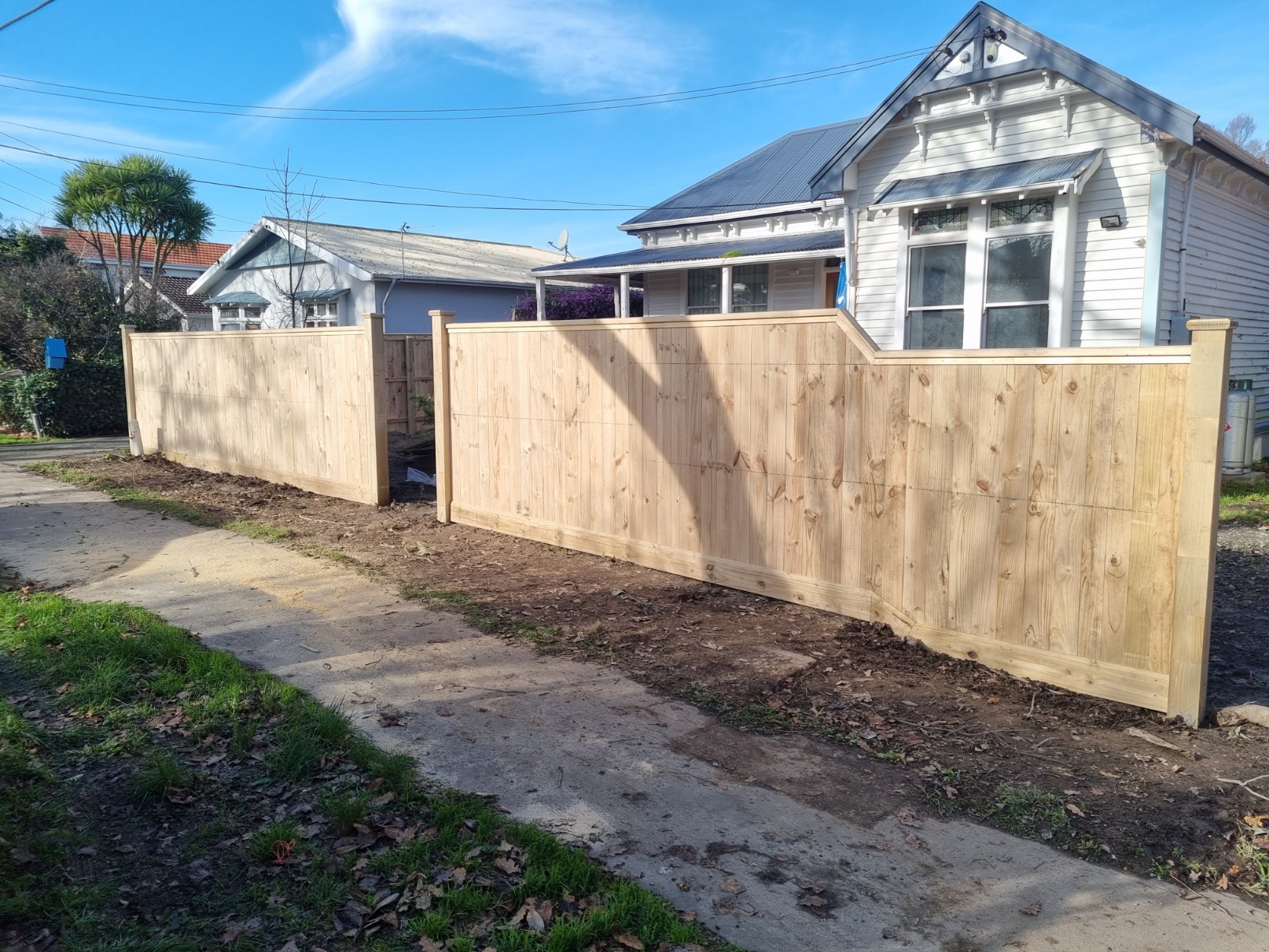 New timber boundary fence in front of a white villa